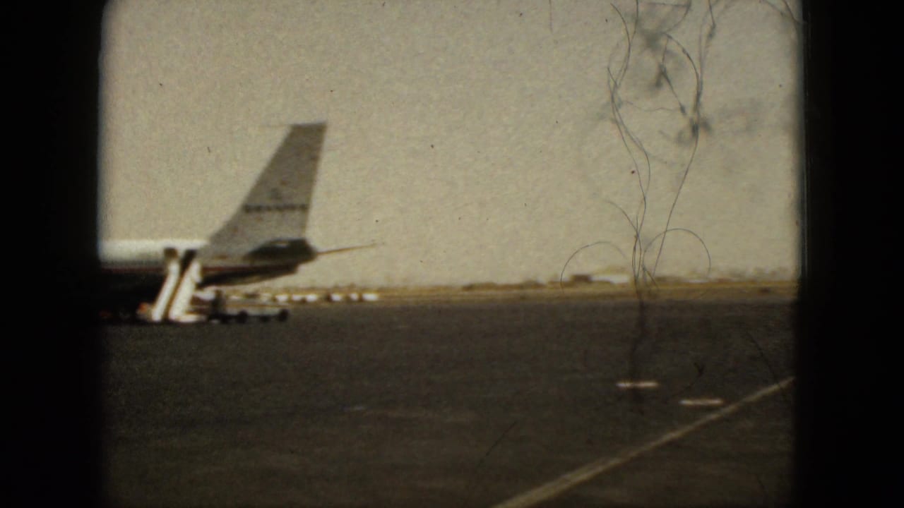 Airplane tail and boarding stairs on a hazy airport tarmac.