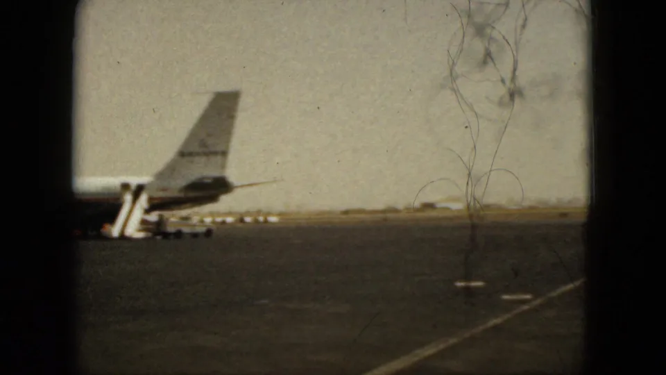 1962 Acapulco airport footage showing an airliner tail, mobile stairs, runway, and distant flat landscape.