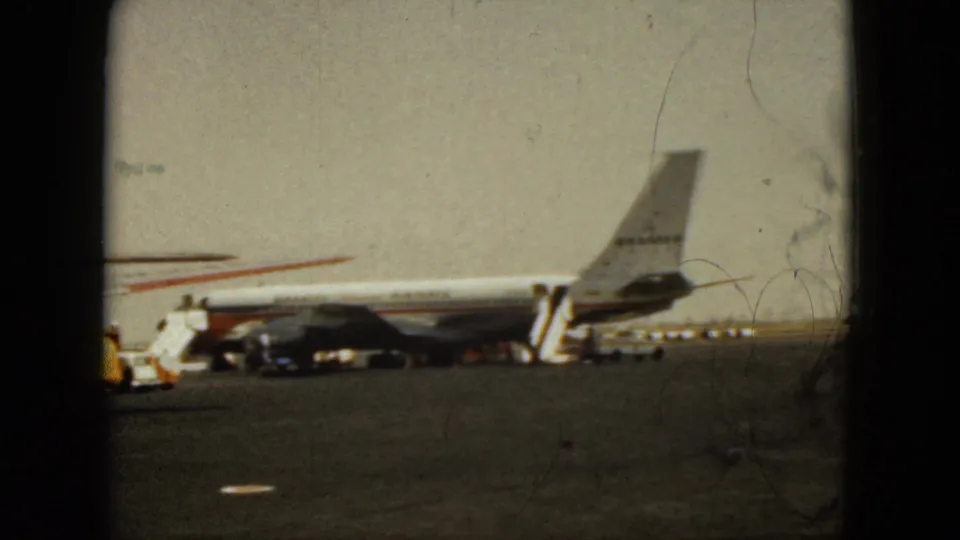 1962 Acapulco tarmac frame centered on the rear of a commercial jet with stairs, carts, and soft 8mm color fading.