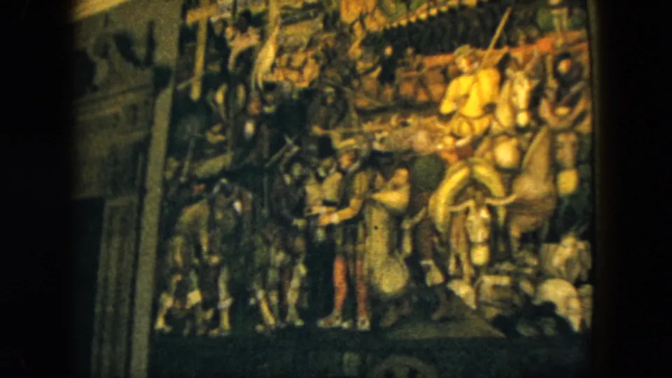 1962 Acapulco home-movie frame showing the large tapestry in a museum gallery, with horsemen, soldiers, and shadowed foreground edges.