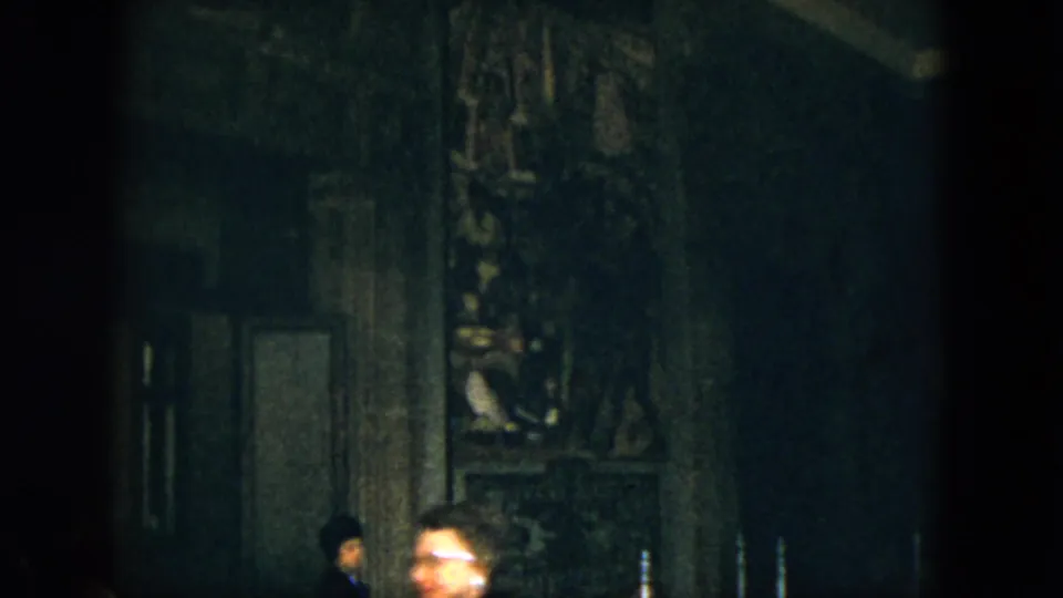 Soft 8mm frame from Acapulco showing partial adult visitors against a dark historic-looking interior wall.