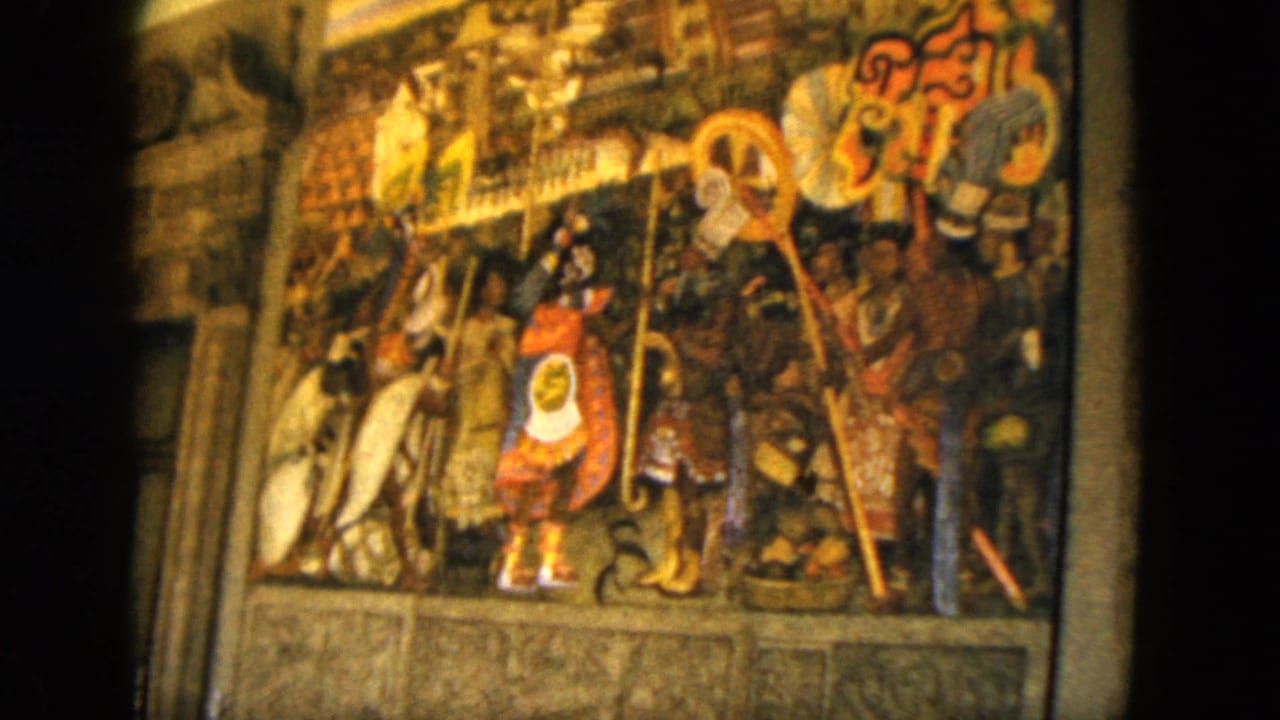 1962 Acapulco travel footage frame holding on the mural's central red-and-blue figure and surrounding painted figures with staffs.