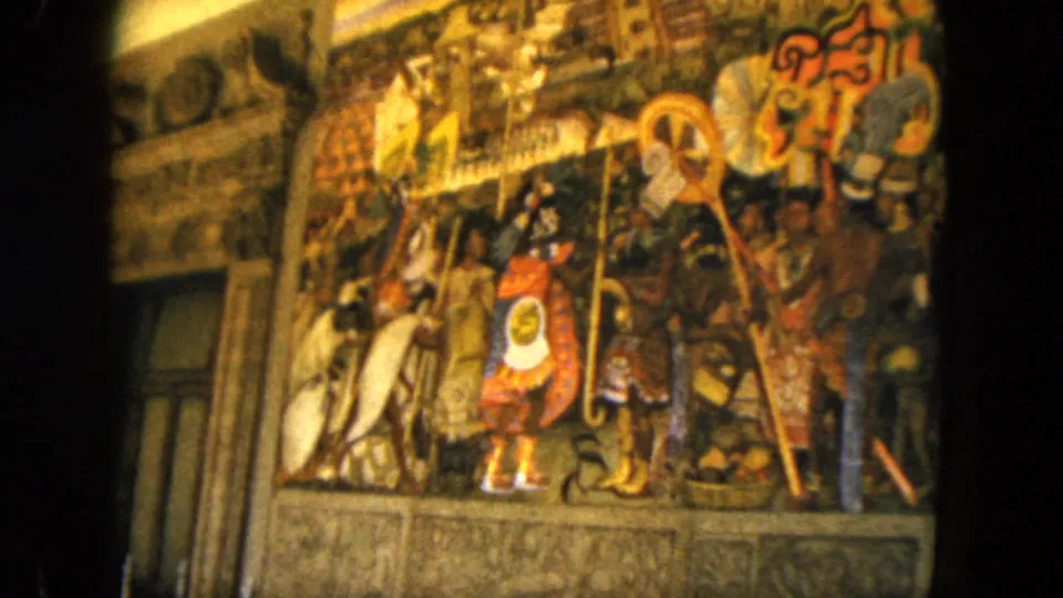 1962 Acapulco 8mm frame showing an angled visitor view of a detailed mural beside an interior wall or doorway edge.