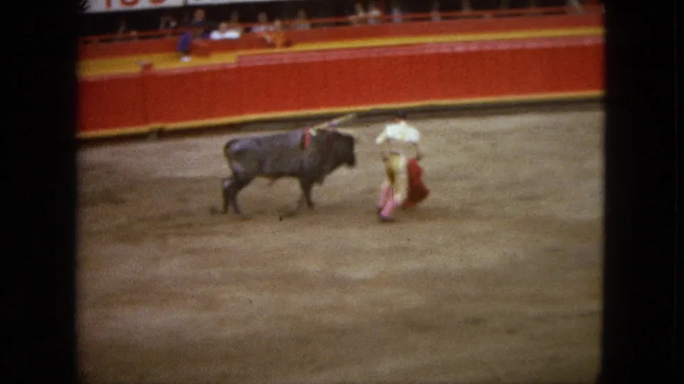 In Acapulco, Mexico, 1962, a matador in light attire holds a red cape near a dark bull inside a bullfighting arena.