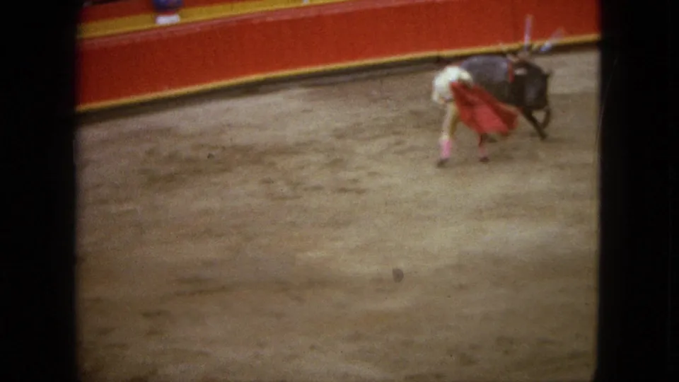 1962 Acapulco home-movie frame showing a bull close to the matador during a cape pass in the arena.