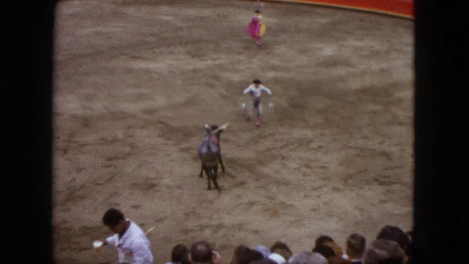 1962 Acapulco bullring view with a dark bull facing a matador in light clothing as spectators watch from the stands.