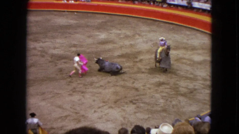1962 Acapulco bullring footage showing a matador with a bright pink cape beside a dark bull, with a horseman and spectators visible.
