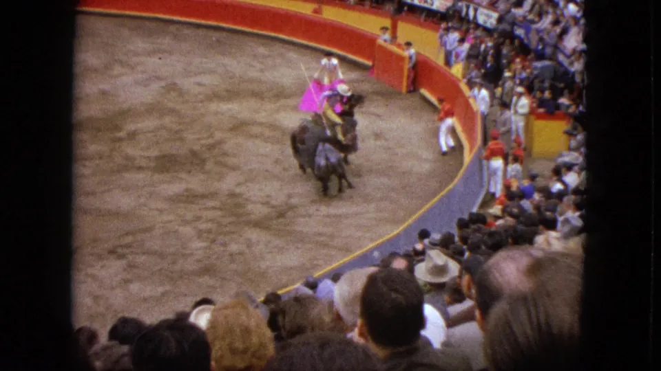 A 1962 Acapulco bullfighting moment shows the pink-caped matador moving near a bull and mounted rider in a crowded arena.
