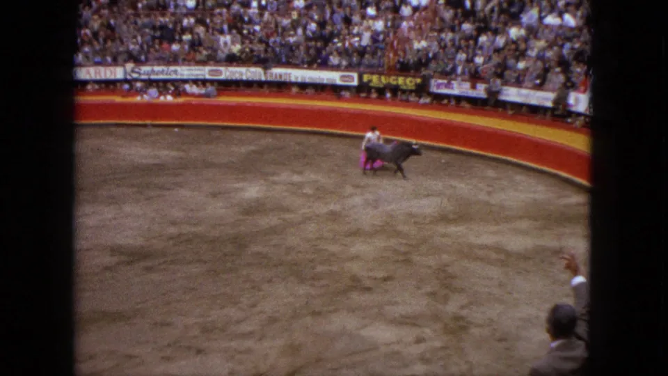 1962 Acapulco bullring view showing a matador with a pink cape confronting a dark bull before packed stands.