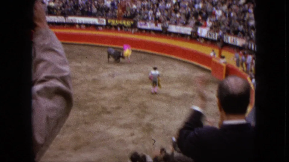 1962 Acapulco spectator-shot frame with nearby viewers in the foreground and a matador working the bull below.