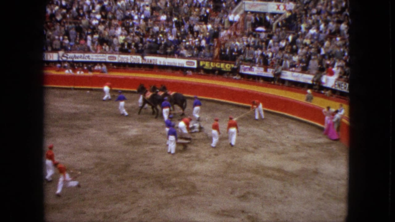 Elevated 1962 Acapulco arena view with horses, matadors, and a crowded bullfighting audience behind red barriers.