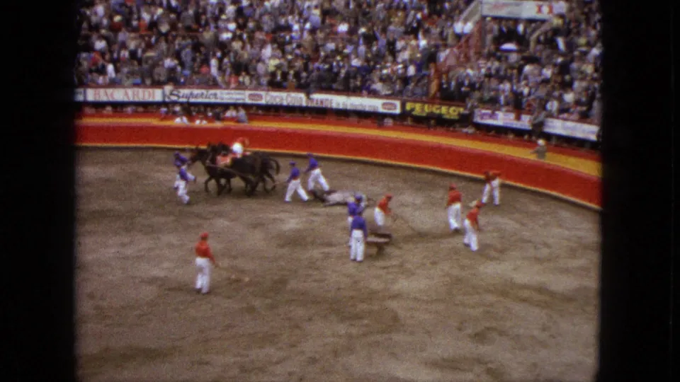 1962 Acapulco bullfighting frame with matadors, horses, a bull, and advertising-lined stands in view.