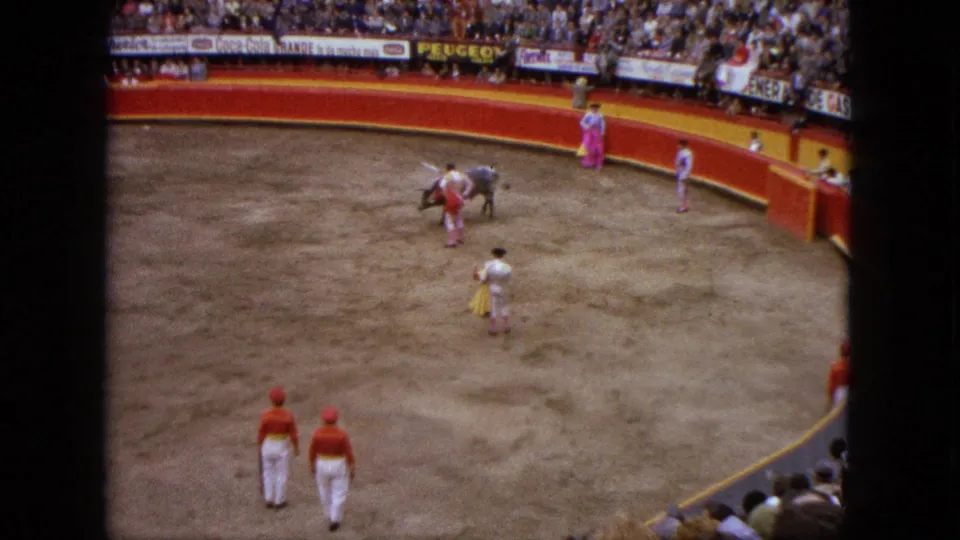 1962 Acapulco bullfight footage shows a bull near a matador in red and white, with attendants, spectators, and arena signage visible.