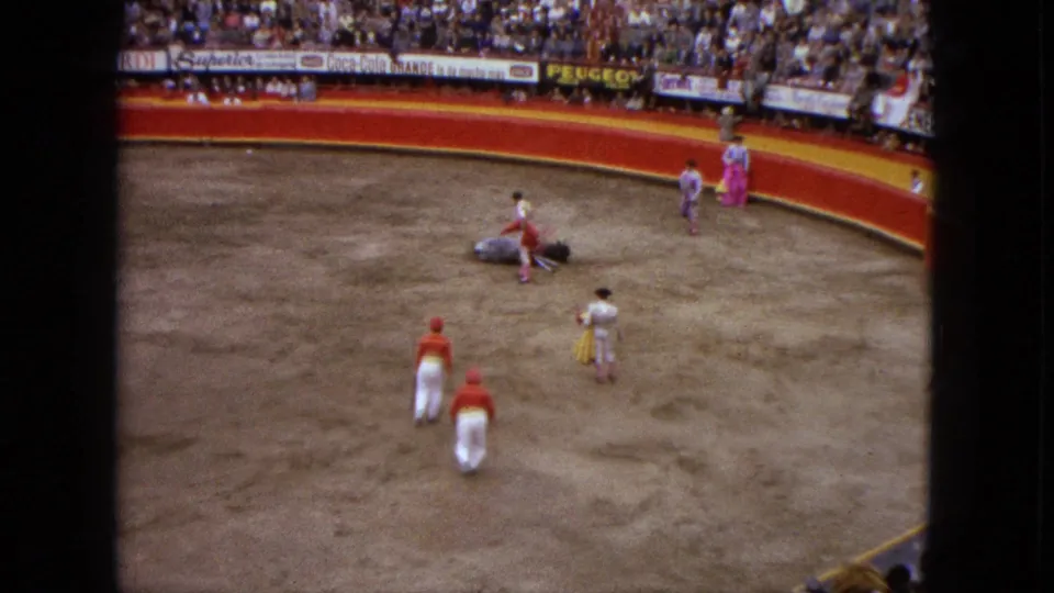 1962 Acapulco bullfight footage shows the bull down on the ring floor while matadors and attendants move toward it before a packed crowd.