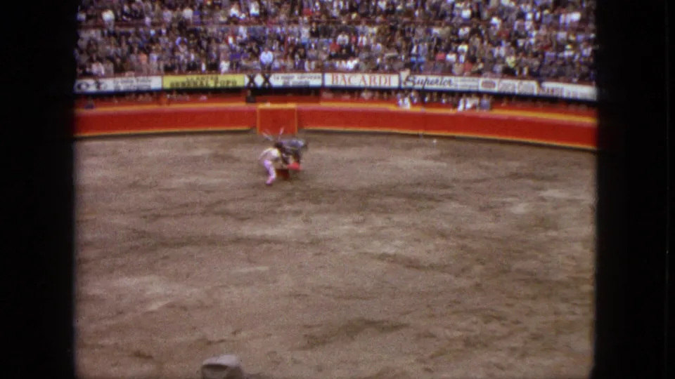 A wider 1962 Acapulco bullring view shows the matador, bull, crowd seating, red barrier, and advertising boards.