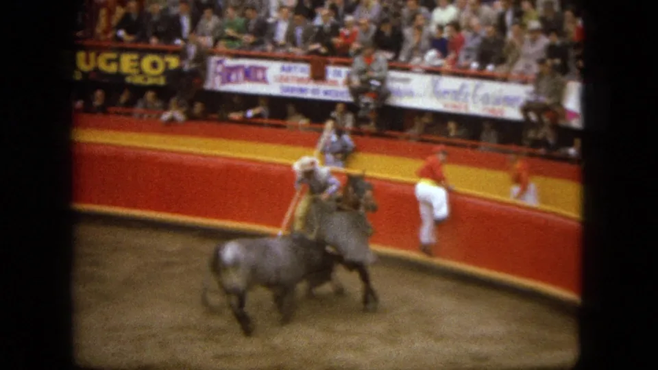 A bull charges near a mounted fighter and horse in the Acapulco arena, with spectators and signage behind them.