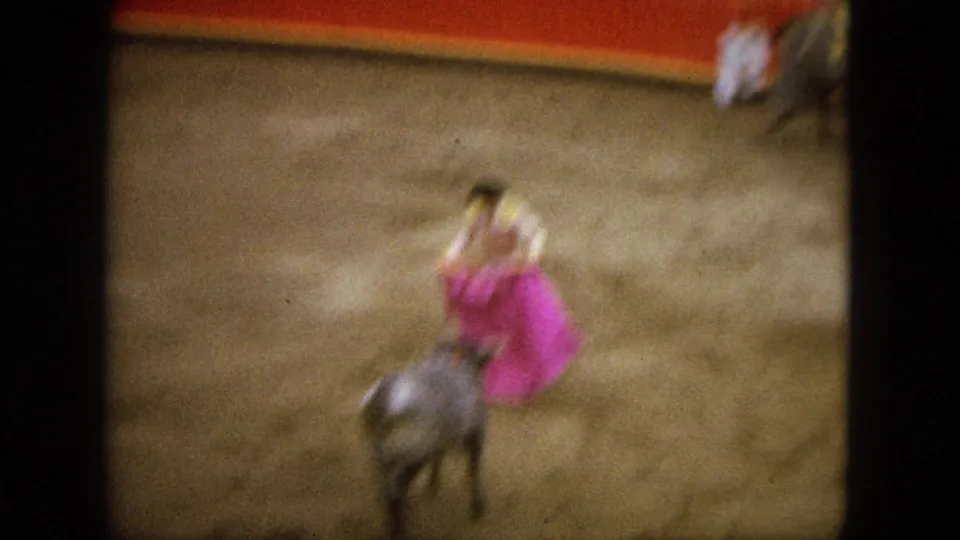 Soft, motion-blurred 1962 Acapulco frame showing the matador and pink cape as the grey bull moves through the arena.