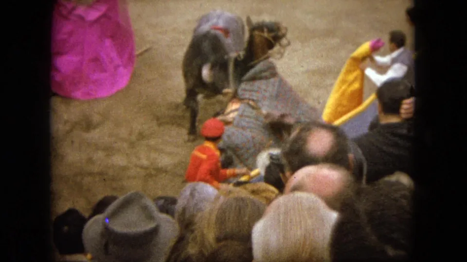 In the 1962 Acapulco arena, the bull and horse remain near handlers with bright capes while spectators fill the foreground.