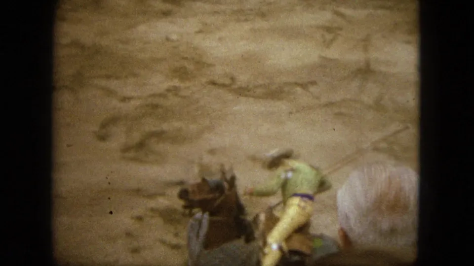 1962 Acapulco 8mm frame showing a mounted rider moving through the dusty arena with another horse partly blurred in foreground.