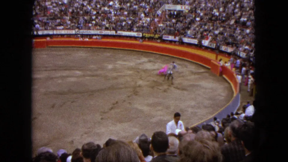 Wide 8mm spectator view in Acapulco showing the bull and matador after a cape pass inside the ring.