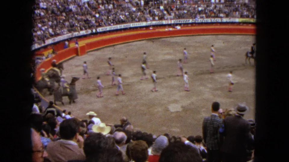1962 Acapulco home-movie view of a bullring procession with riders, camels, walkers, and a packed audience.