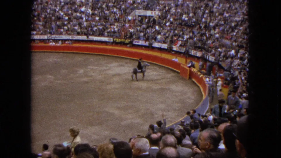 1962 Acapulco home-movie frame showing a rider on a grey horse in a crowded bullfighting-style arena.