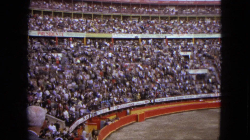 Final 1962 Acapulco stadium frame with a dense crowd, foreground spectator, and visible advertising around the arena boundary.