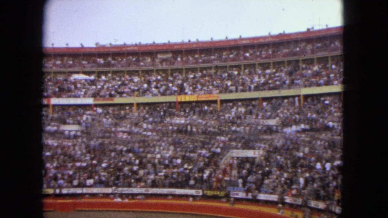 Packed arena stands seen through a dark 8mm contact-sheet frame edge.