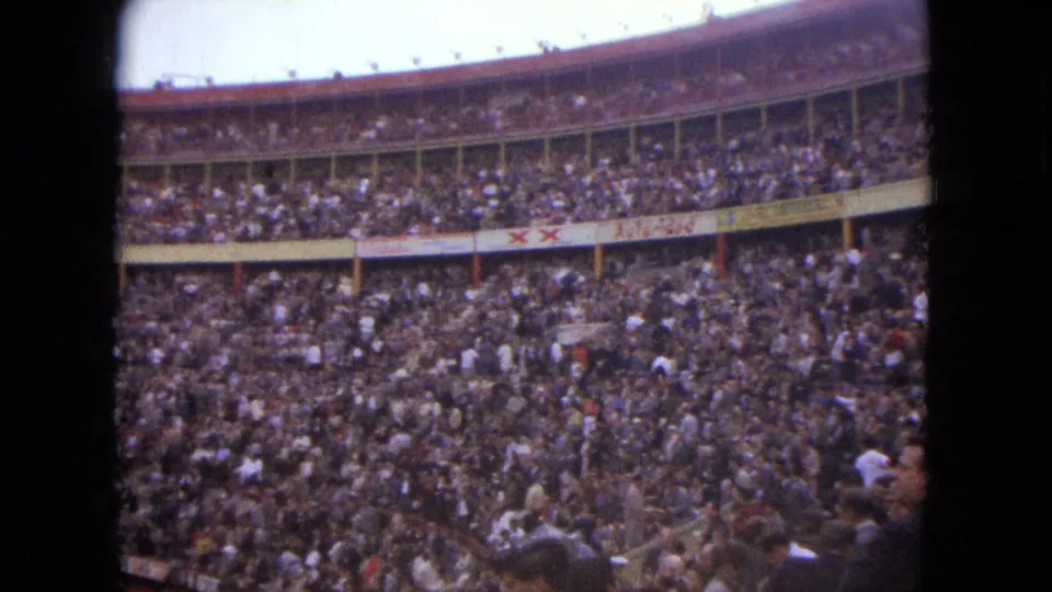 Interior view of a crowded Acapulco bullring, with spectators filling the curved tiers and arena edge visible below.