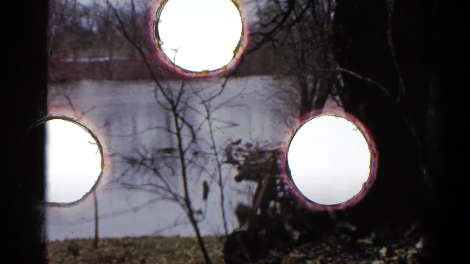 1961 Wauconda pond frame with visible 8mm perforation holes and physical-film wear over the landscape.