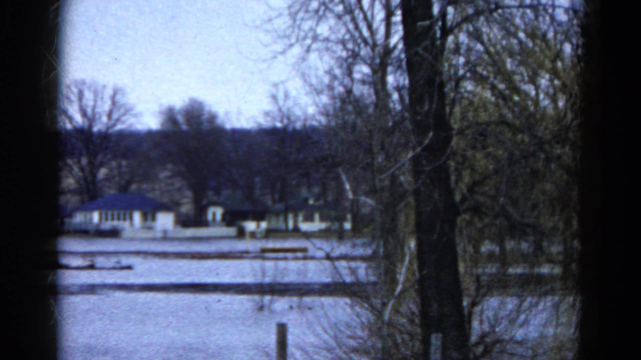 1961 Wauconda, Illinois 8mm still showing low buildings beyond snow, with leafless trees and dark frame borders.