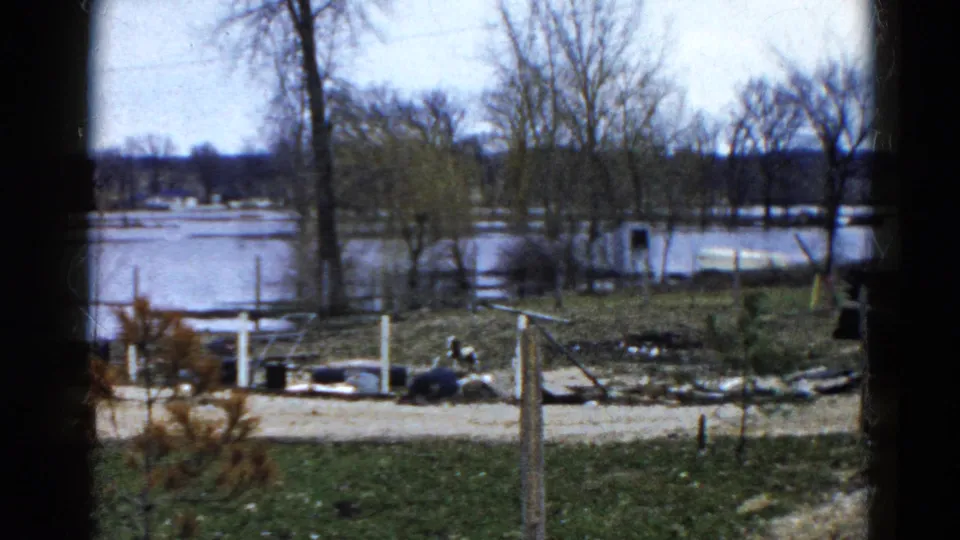 1961 Wauconda, Illinois home-movie frame of floodwater across a lakeside property, seen from behind a window.