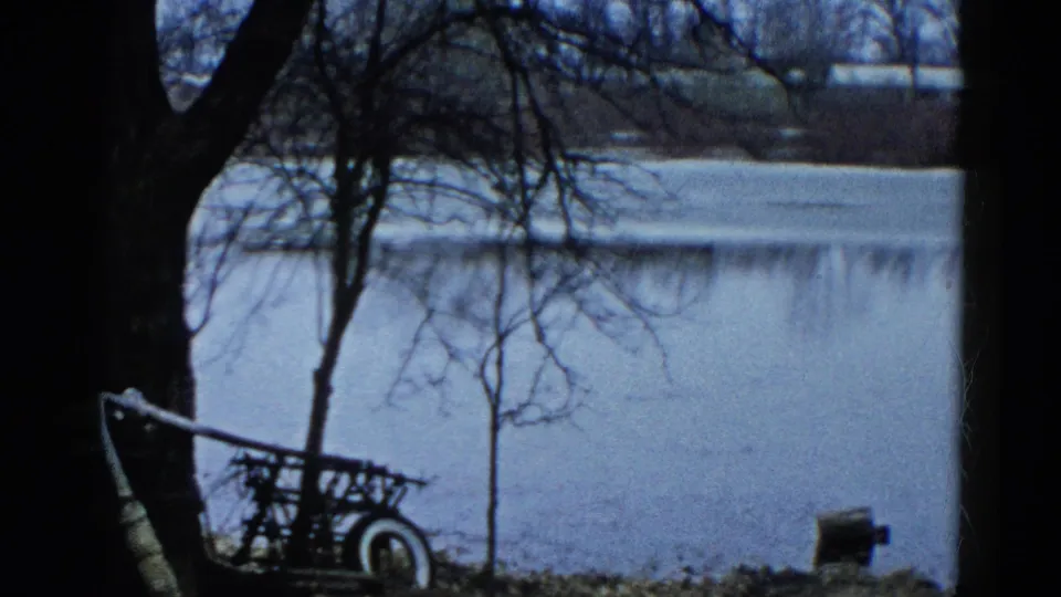 1961 Wauconda, Illinois frame showing a small cart or trailer near a pond or flooded area, with bare trees in the foreground.