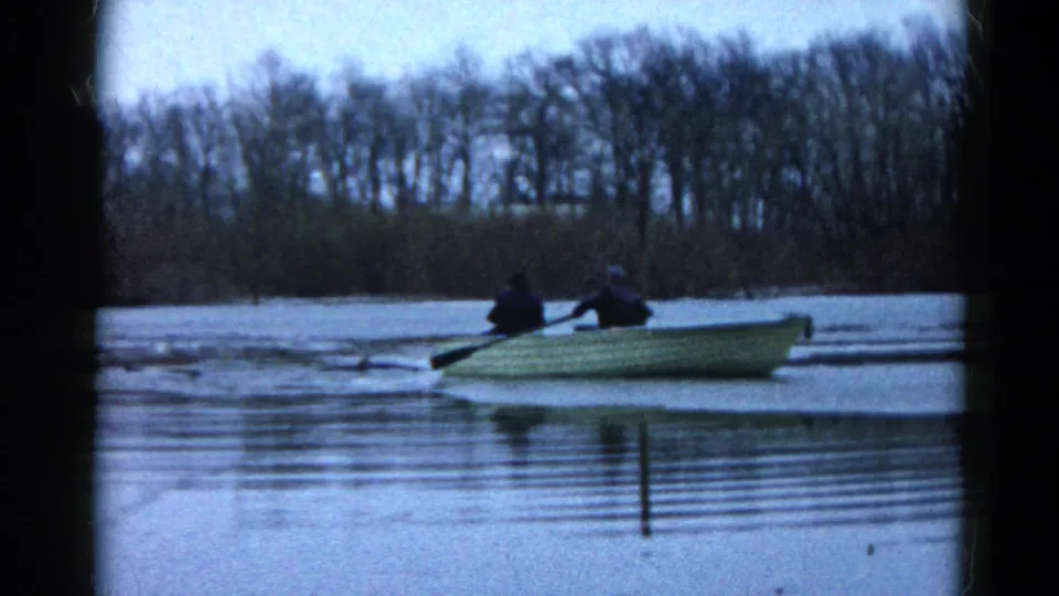 The 1961 Wauconda lake scene shows two men in a small rowboat, seen in soft 8mm color against bare trees and still water.