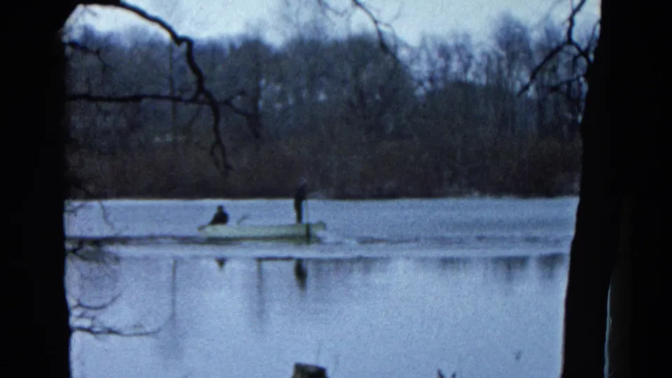 A distant rowboat crosses the lake in 1961 Wauconda footage, with one person seated and another standing near an oar.