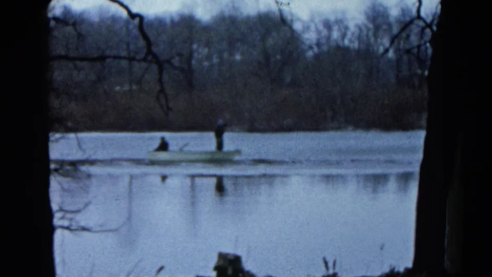 1961 Wauconda, Illinois lake scene with one person seated and one standing in a small boat, framed by dark trees.
