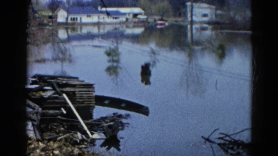 Floodwater reflects houses and shoreline debris in a Wauconda residential area recorded on 8mm film in 1961.