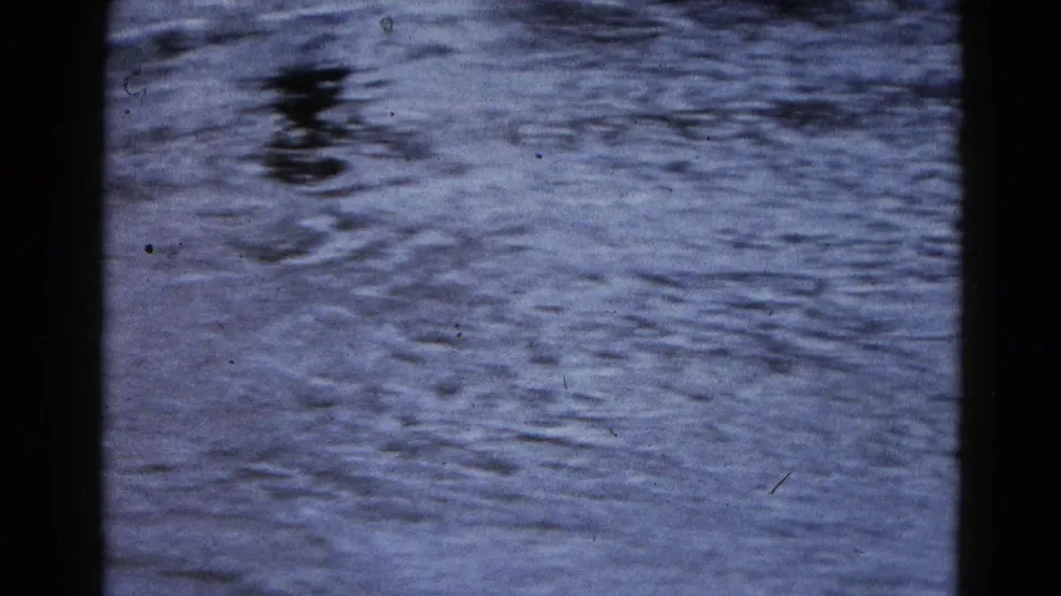 Floodwater spreads across a Wauconda road in this 1961 8mm frame, with reflections and pavement barely visible.