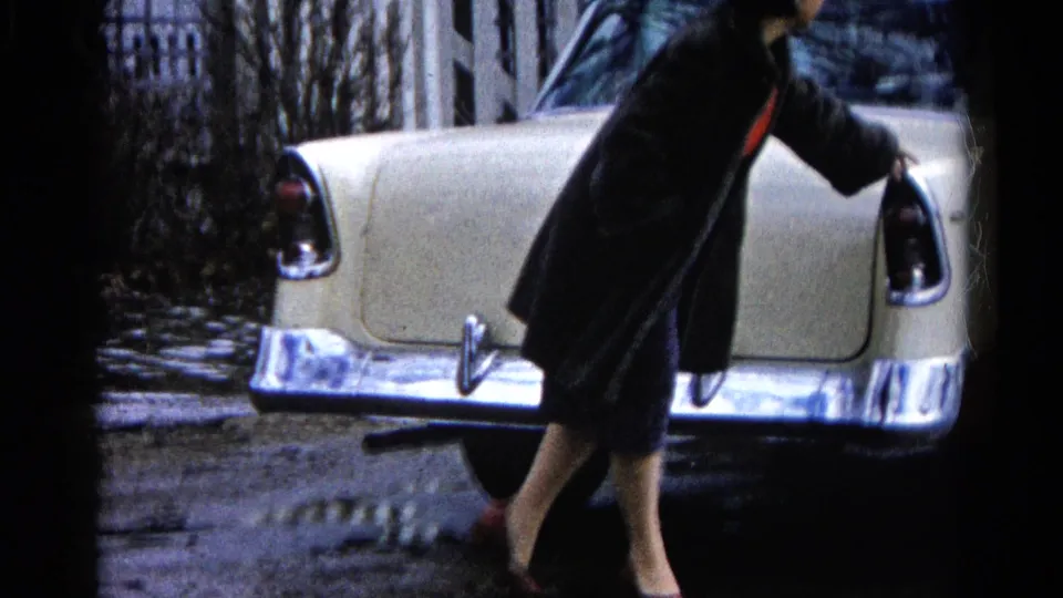 The woman passes close to the parked Chevrolet's rear in Wauconda, Illinois, her dark coat and red shoes visible beside the chrome bumper.