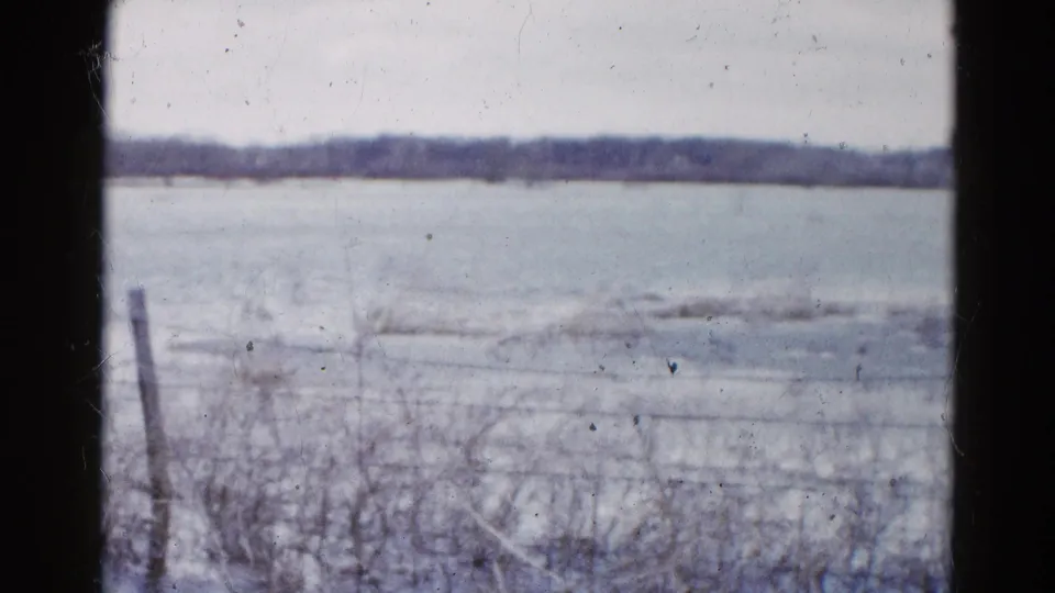 Wauconda winter landscape on 8mm film, showing a quiet frozen field, wire fence, and distant tree line.