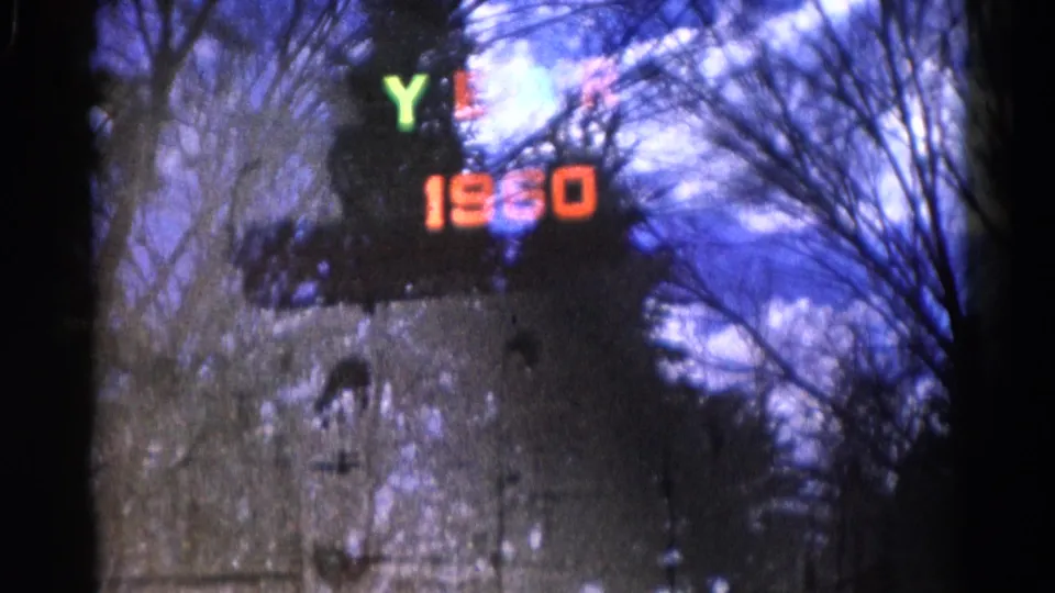 The 1961 Wauconda home-movie frame shows colored YEAR letters and orange 1960 digits over reflected or seen-through trees.