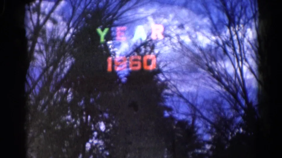 Final 8mm frame from Wauconda showing "YEAR 1960" in colored letters against a deep blue sky, with winter branches in silhouette.