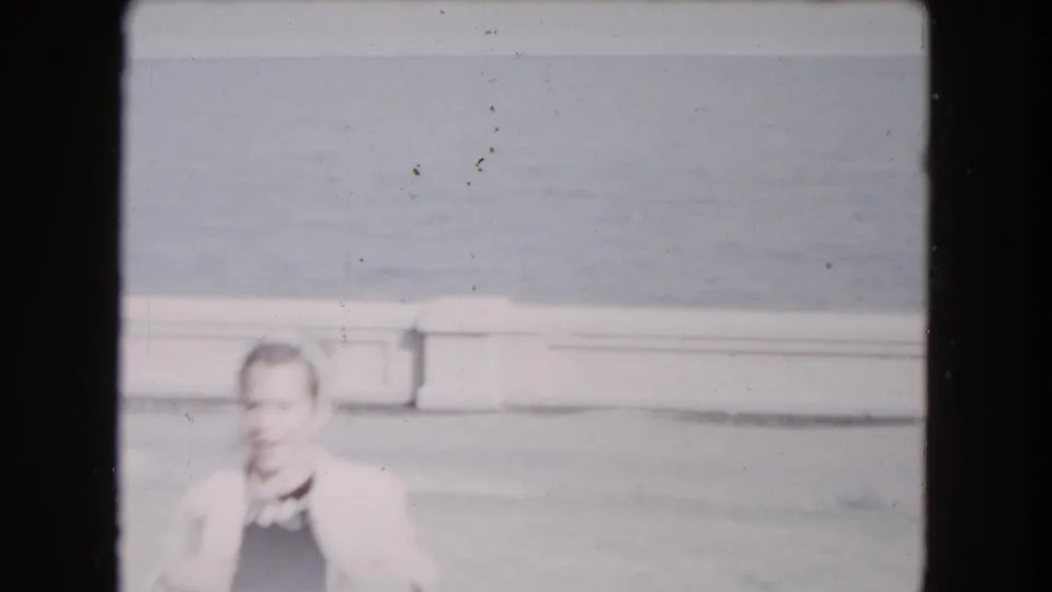 1961 South Carolina 8mm frame showing an adult man in a light jacket near a pond or water edge.