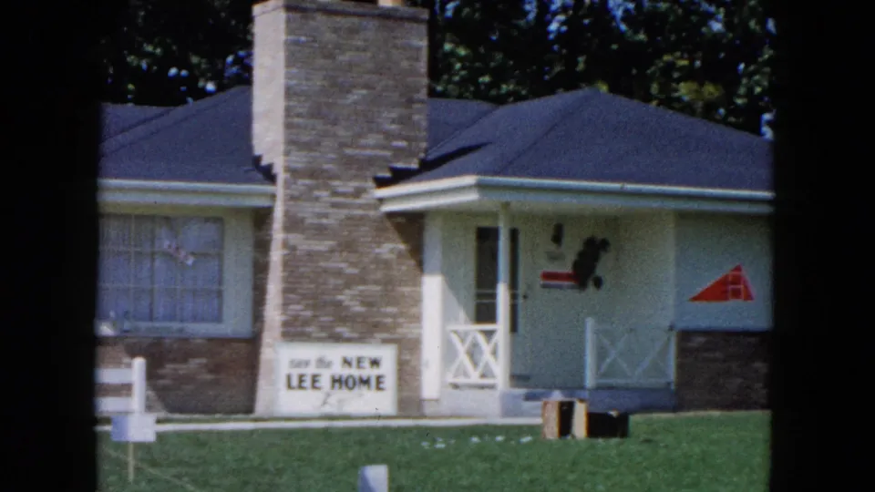 1961 South Carolina home-movie view of a model-style house facade with porch rail, window, chimney, and new Lee home sign.