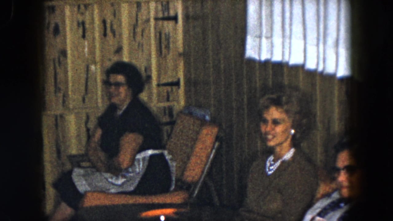 A 1961 South Carolina frame shows older women seated in upholstered chairs, with one woman smiling toward the camera.