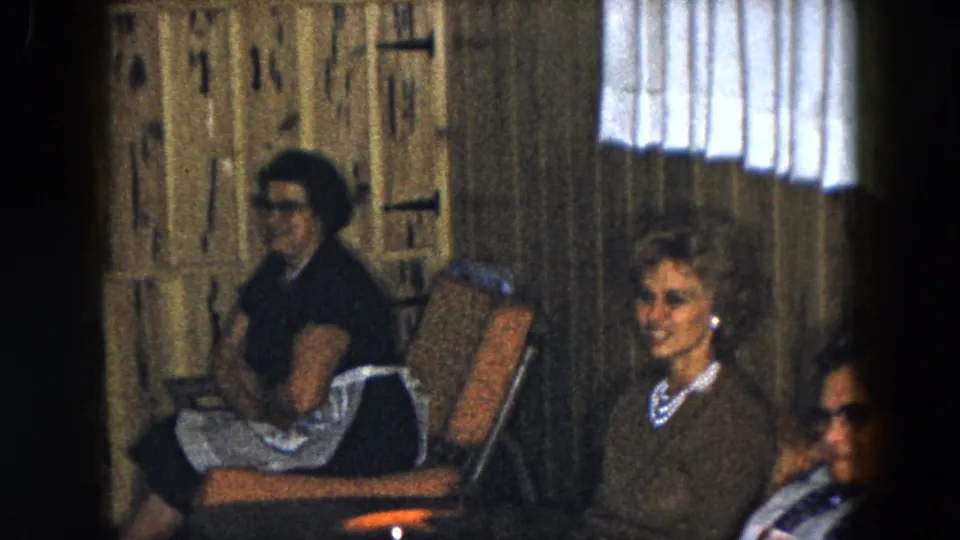 A 1961 South Carolina frame shows older women seated in upholstered chairs, with one woman smiling toward the camera.