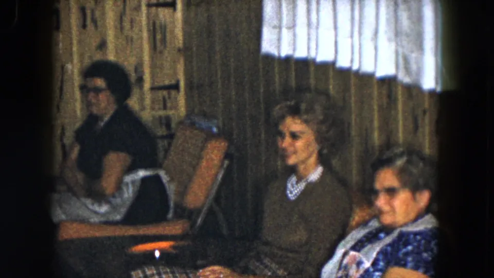 This 1961 South Carolina frame shows three older women seated together in a wood-paneled indoor lounge setting.