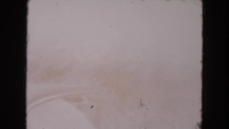 Faded 8mm frame showing a very bright car-side view, with faint outlines of window trim and vehicle body visible.
