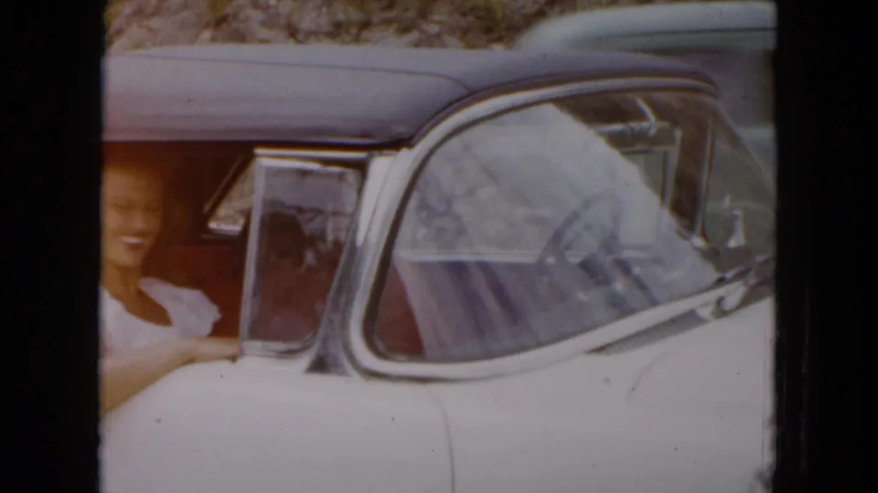 1961 South Carolina home-movie frame of a smiling woman in the passenger seat of a white convertible.