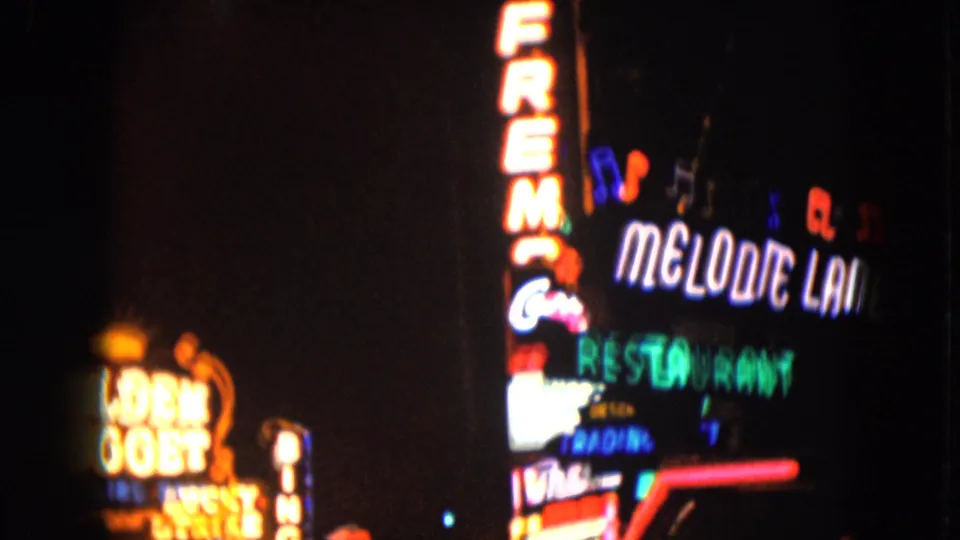 1961 Nevada frame with Melodie Lounge Restaurant signage and partial Golden Nugget neon visible at night.